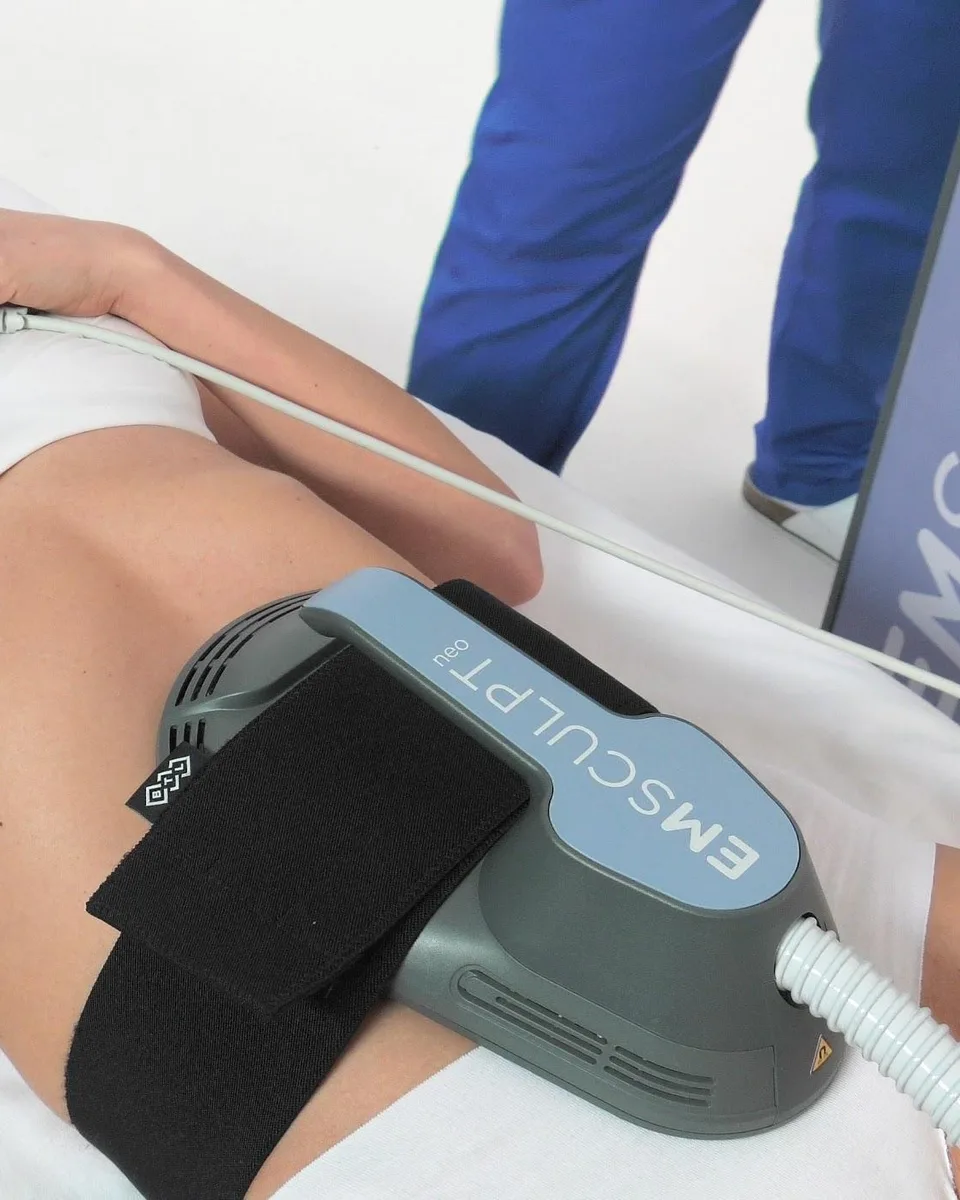 Emsculpt NEO applicator by BTL strapped over the abdomen during a body contouring session